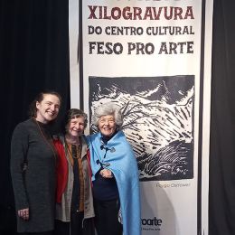 Noni Ostrower entre as curadoras da mostra, Silviane Lopes (à esquerda) e Izadora Andrade. No banner, obra de Fayga Ost